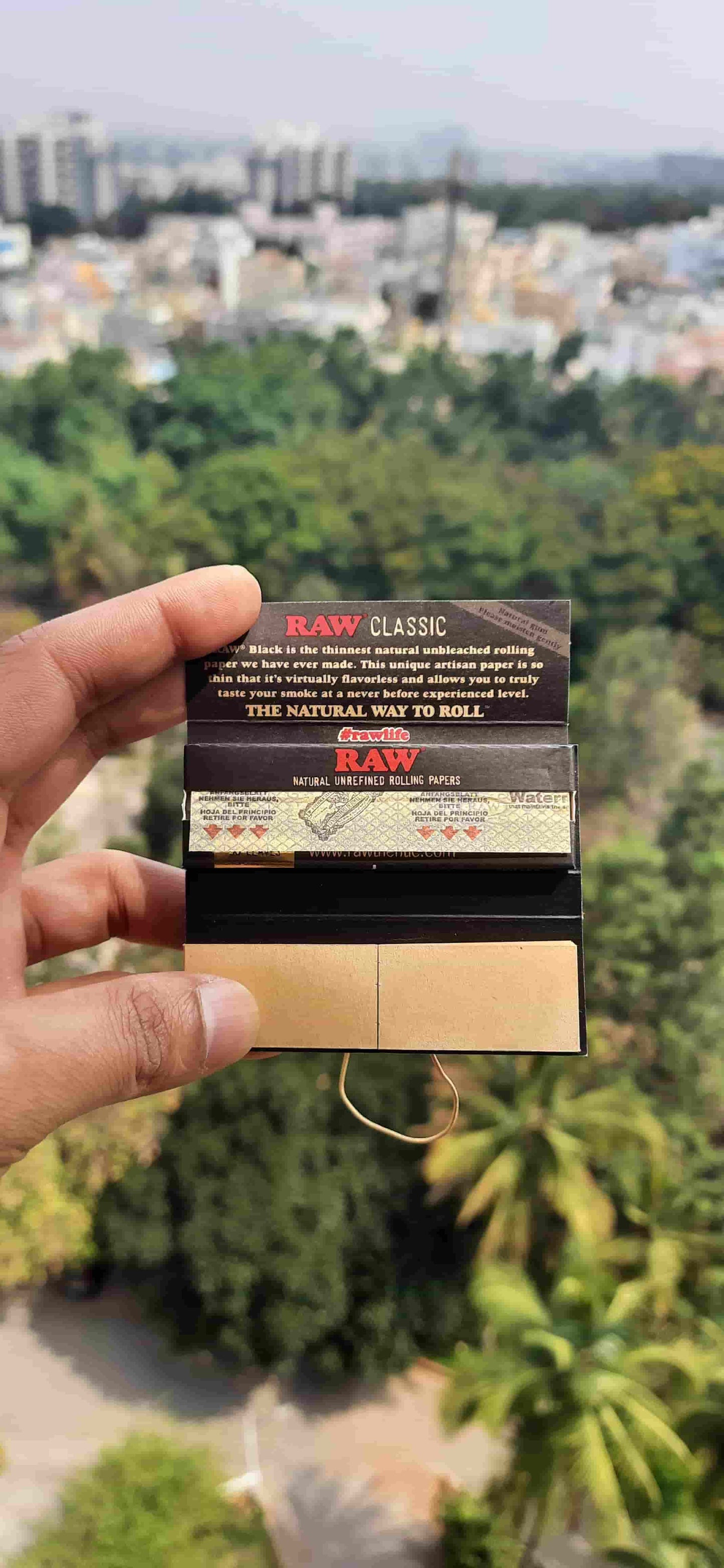 RAW Black Connoisseur Rolling Paper 1 1/4 in hand